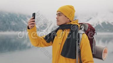 徒步旅行者使用智能手机拍摄冬季自然的照片。 游客崇尚自然，制作照片.. 年轻人